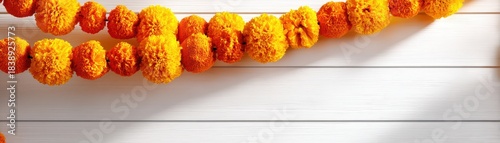 Vibrant marigold flowers arranged in a garland on a wooden background.