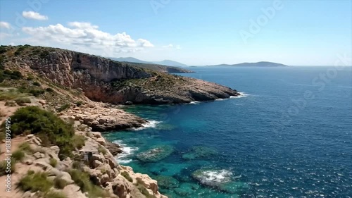Scenic aerial view of a rugged coastline with cliffs, turquoise water, and distant islands under a blue sky