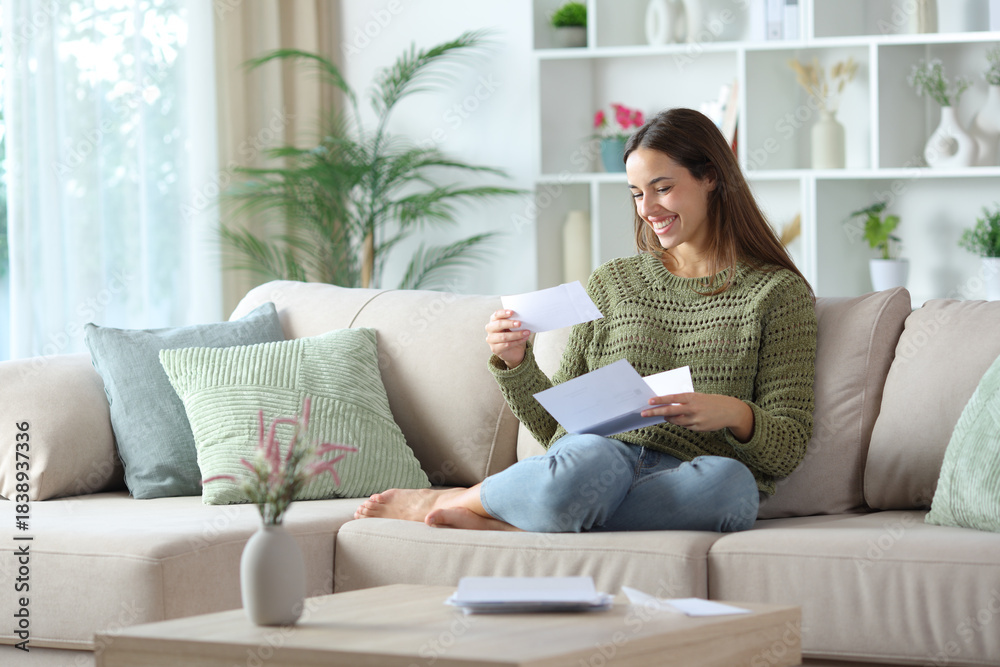 Fototapeta premium Happy woman in green reading check from letter at home