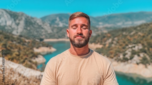 Man practices mindfulness near a lake surrounded by mountains in daylight