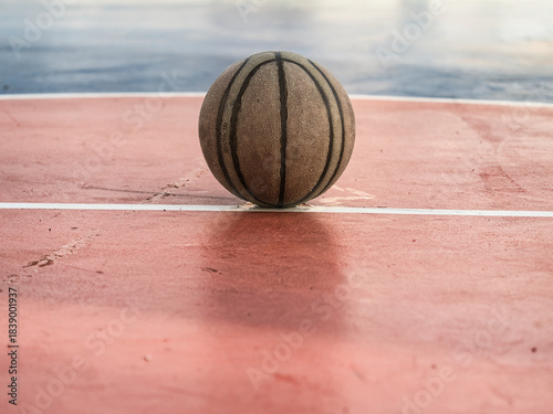 Old basketball on the court has standing water.