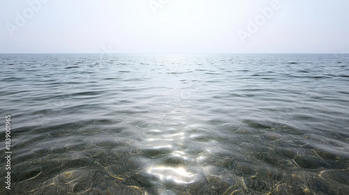 Fototapeta Naklejka Na Ścianę i Meble -  Calm sunlit sea with gentle ripples and clear shallow water reflecting light