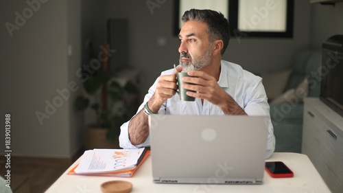 Bild auf Leinwand Mature man working remote looking away drinking coffee