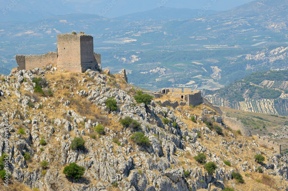 Obraz premium Acrocorinth fortress ruins overlooking the Corinthian valley. Acrocorinth fortress ruins standing on a rocky hill under a clear sky. Peloponnese, Greece