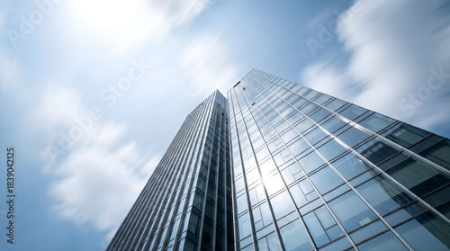 Modern glass skyscraper reflecting blue sky and white clouds building architecture