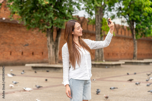 Obraz na plátně Young Asian Woman Tourist Using Phone at Tha Phae Gate in Chiang Mai Thailand