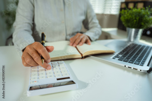 Φωτογραφία woman use the calculator and take notes with calculations about the expenses at the office