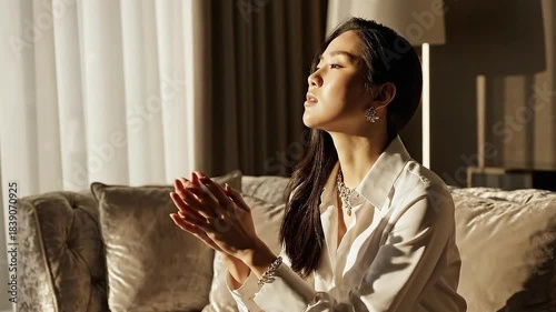 Woman Praying in Luxurious Interior with Soft Golden Light Streaming Through Curtains