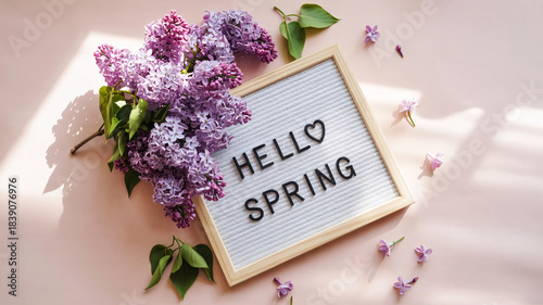 Hello Spring Letter Board with Heart Symbol and Lilac Flowers on Soft Pink Background