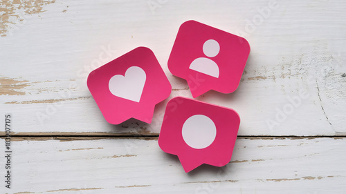 Social Media Notification Icons – Pink Heart, Profile, and Comment Symbols on White Wooden Background