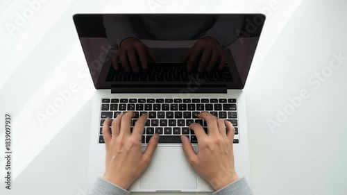 Top-down view of hands typing on a laptop keyboard, showcasing productivity and technology use.