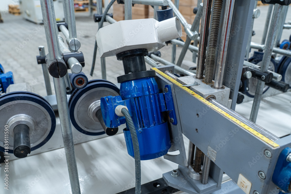 Fototapeta premium Blue industrial motor with adjustment scale and rollers on processing machine