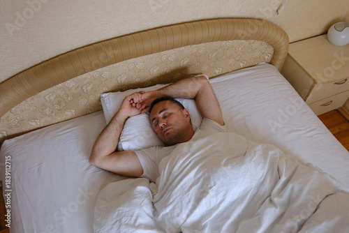 Caucasian man guy lying on bed wake up stretching rubbing eyes male home bedroom good morning sleepy awake wellbeing comfortable new day householder relaxed awakening weekend apartment hotel .