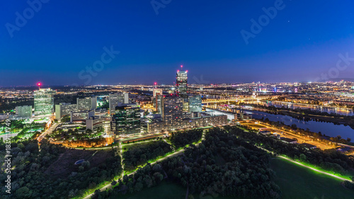 Aerial panoramic view over Vienna city with skyscrapers, historic buildings and a riverside promenade day to night timelapse in Austria.