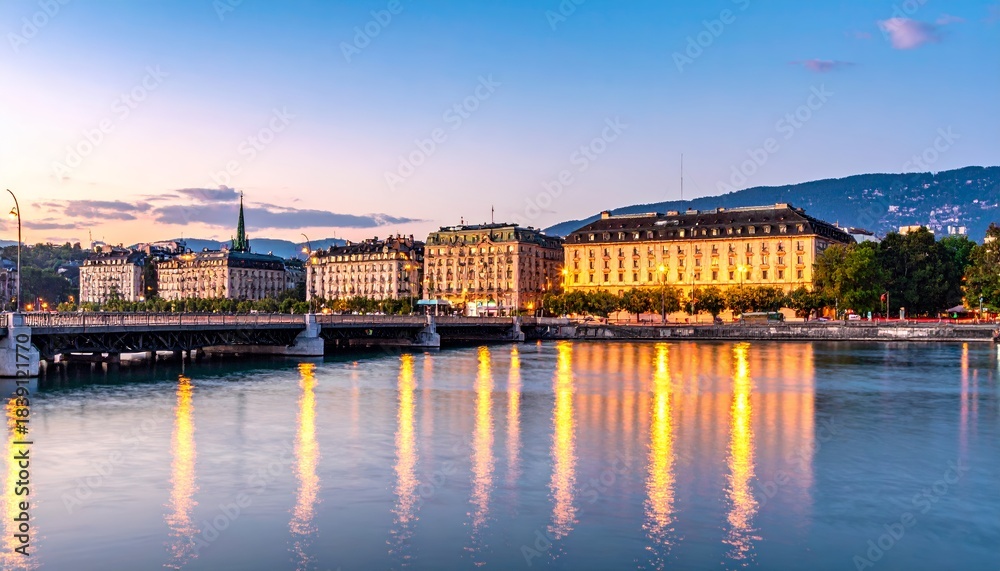 Obraz premium Beautiful Sunset over Geneva Cityscape with Lake Geneva and Illuminated Buildings Reflected in Water.