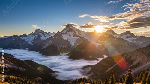 Witness a breathtaking panoramic view of a majestic mountain range at sunrise or sunset, with golden sun rays piercing through the sky and creating a stunning lens flare. Snow-capped peaks rise dramat