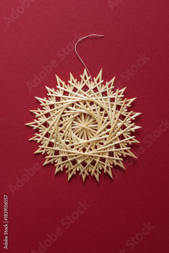 Straw snowflake. Snowflake are made of straw on a red background. Christmas decor. Top view. Straw weaving. Lutsk, Ukraine