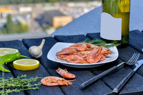 plate of boiled shrimps on a black table with prosecco on a landscape background
