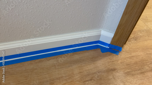 Painter's tape along white baseboard corner