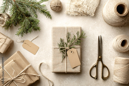 Neutral Eco-Friendly Holiday Gift Wrapping Flat Lay with Kraft Paper, Twine and Evergreen on Light Textured Background