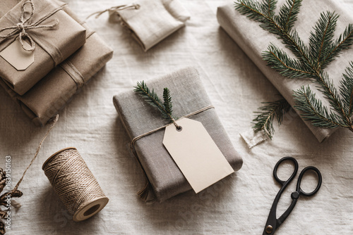 Neutral Eco-Friendly Holiday Gift Wrapping Flat Lay with Kraft Paper, Twine and Evergreen on Light Textured Background