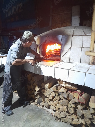 Fotografie Person using a wood-fired oven, which is a type of traditional oven made by hand