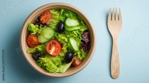 A brightly lit, minimalist overhead shot of a fresh, healthy salad in a round, natural brown paper bowl, suitable for takeaway or an eco-friendly meal. 
