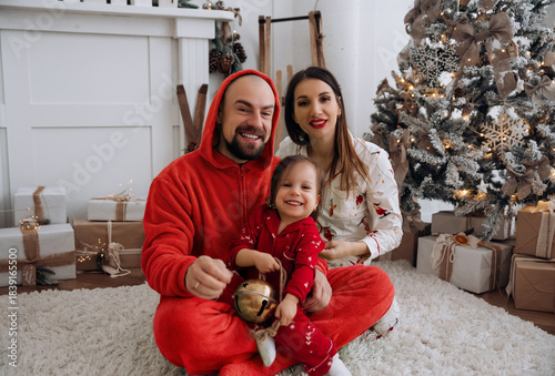 Family enjoys a festive moment together at home during the holiday season while wearing matching pajamas and celebrating with Christmas decorations around them
