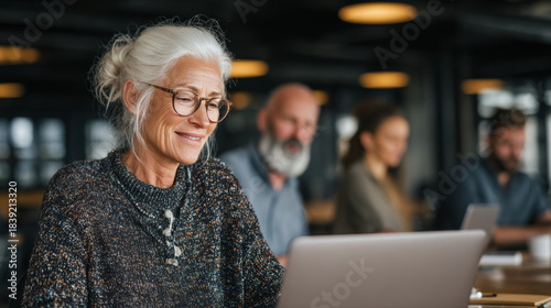 happy elderly woman working on a laptop in a modern office, working long life and increasing the duration of an active life