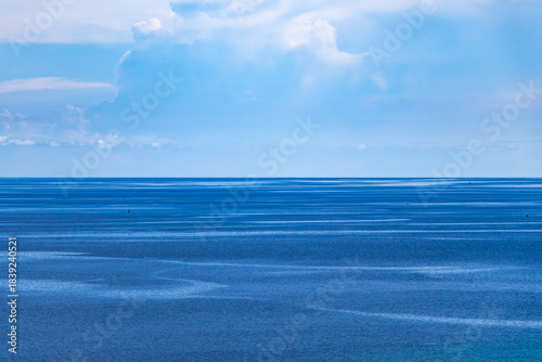 Fototapeta Naklejka Na Ścianę i Meble -  minimalist shot of the horizon with blue water and soft clouds