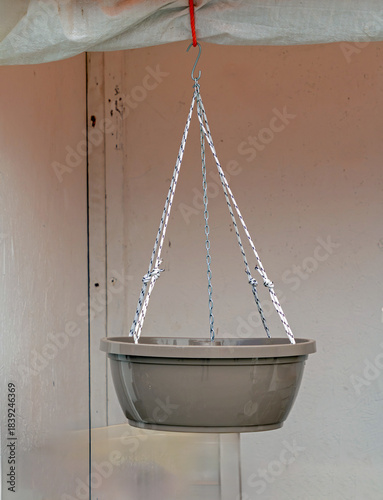 Empty plastic flower pot hanging from a ceiling