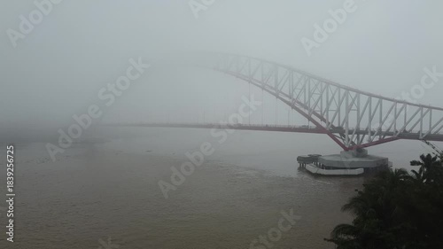 Red and White Bridge, Kutai Kartanegara, East Kalimantan, Indonesia, Aerial view with car and motorbike traffic during fog, December 27, 2023 