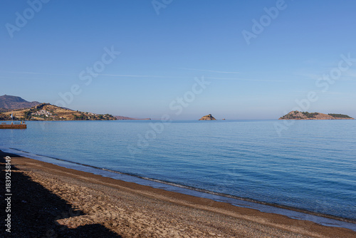 Serene coastal landscape with calm sea and distant islands.