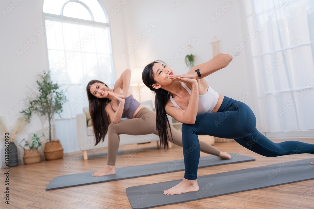 Obraz premium Two women practice yoga together in a bright room with large windows in the morning