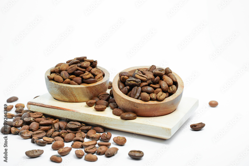 Fototapeta premium coffee beans in a rustic wooden bowl, scattered on a light wooden board and an isolated white background