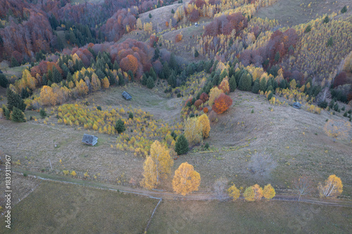 Autumn aerial view of the Transylvanian hills – Rural landscape with colorful trees and traditional cottages at the mountain edge