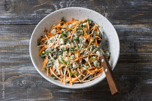 Seaweed and carrot salad mixed with diced egg and creamy dressing in rustic ceramic bowl 