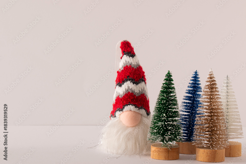 Obraz premium Christmas gnome with long white beard and red hat with decorating trees on white background. Holiday idea.