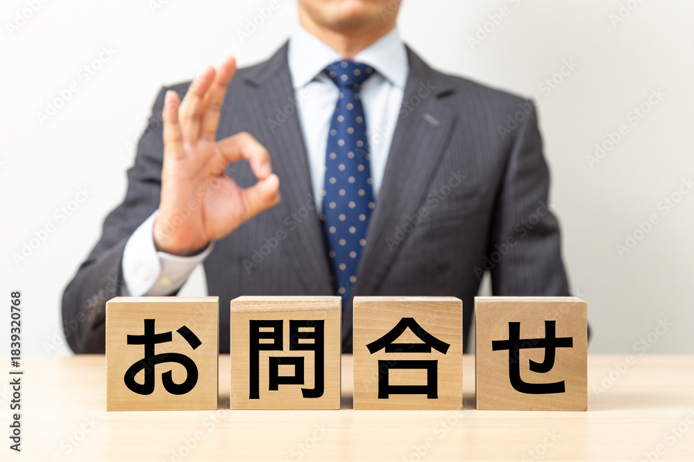 Obraz premium 「お問合せ」と書かれたブロックとOKポーズをするビジネスマン