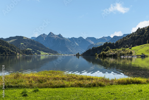 Lake Sihlsee, surrounded by lush green hills and the majestic Fluebrig mountain range in the Swiss Alps near Einsiedeln, Canton of Schwyz, Switzerland