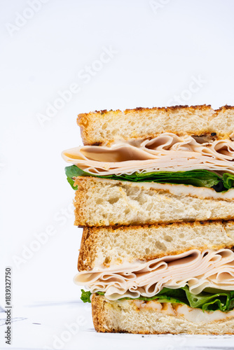 Sándwich de pavo y lechuga apilado sobre fondo blanco