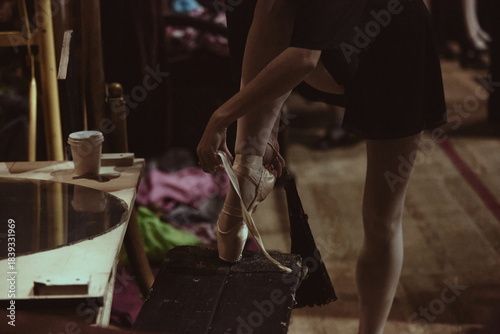 Tableau sur toile Ballet dancer adjusting pointe shoes backstage during final theater rehearsal
