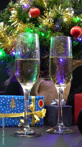 Video verticale, bicchieri di champagne in primo piano, decorazioni natalizie con pacchetti regalo