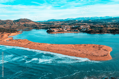 A high-altitude drone photo capturing Liencres Beach and the Pas River estuary, showcasing turquoise waters, golden sand formations, and the surrounding natural reserve in northern Spain.