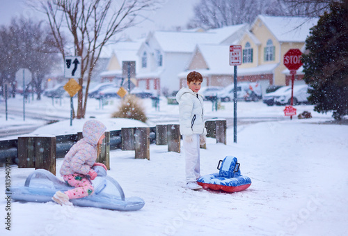 Children Enjoying Winter Sledding Fun on Inflatable Sleds in a Snowy Suburban Neighborhood. Active Winter Playtime