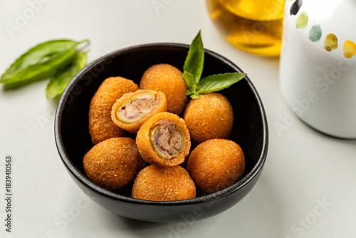 Olive all'ascolana, also known as olive ascolane ripiene, is an Italian appetizer of fried olives stuffed with meat.  Italian Appetizer or antipasto on a light table.