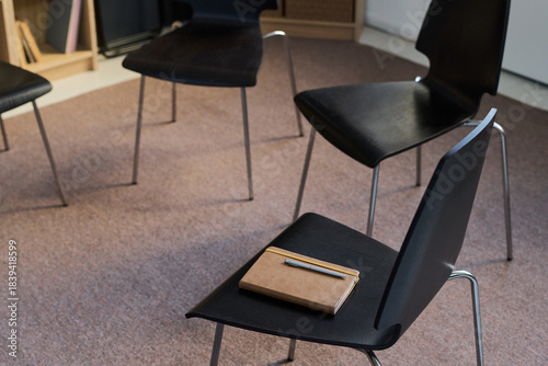 Foto Empty chairs arranged in circle with notebook and pen resting on seat, represent