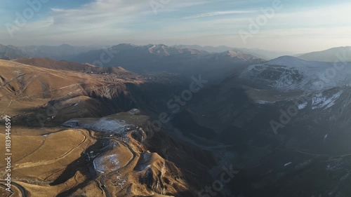 Aerial view of the historic Russia-Georgia Friendship Arch monument situated on a cliff edge near Jvari Pass in the Gudauri mountain area. Early wiinter landscape with beautiful mountains.