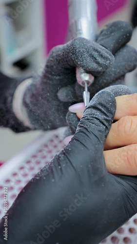 Professional manicurist filing client's nails with a drill for a perfect finish