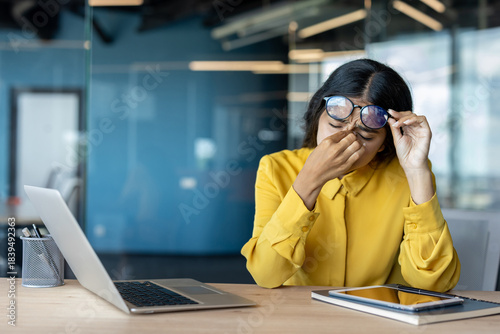 Fotografia Tired and overwhelmed young Indian businesswoman sitting at her office desk
